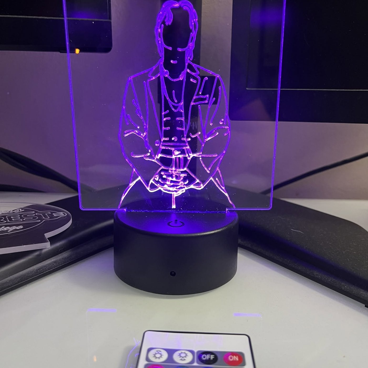 An engraved acrylic panel lit purple on a color-changing LED base with its remote