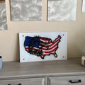 Wall art of the United States filled with an eagle and the American flag, mounted on white acrylic