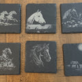 Six slate coasters engraved with horse designs on a wood table