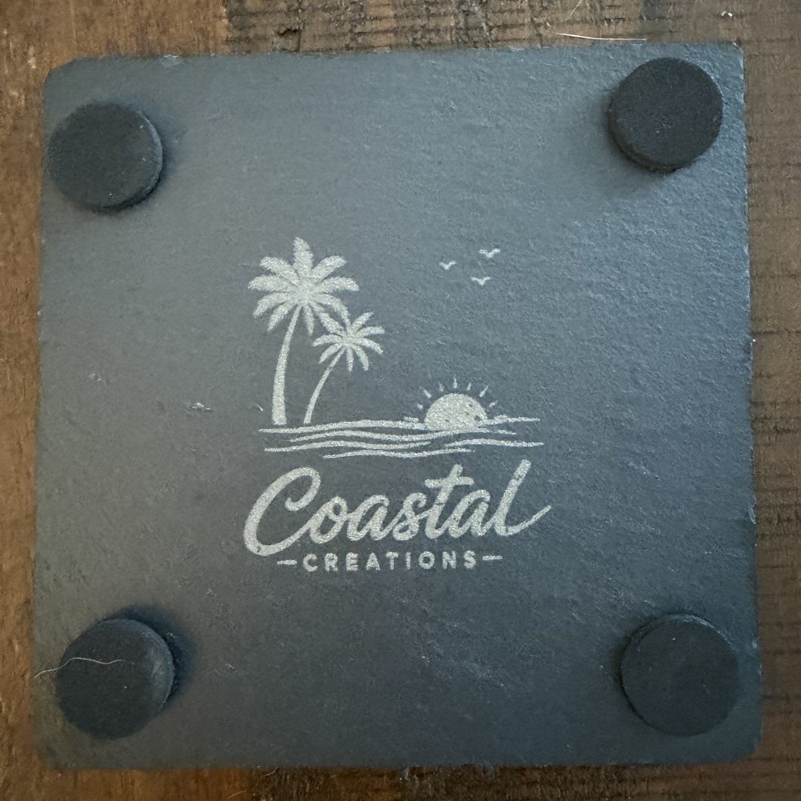 Back of a slate coaster showing felt feet and the Coastal Creations mark
