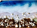 A hand-poured ocean resin beach scene with foam breaking over shells, made in San Diego