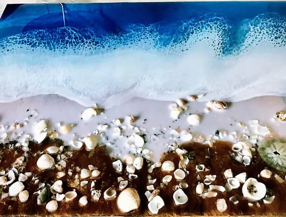 A hand-poured ocean resin beach scene with foam breaking over shells, made in San Diego